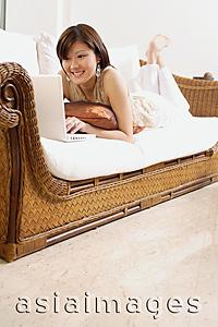 Asia Images Group - Woman lying on sofa using laptop