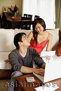 Asia Images Group - Couple in living room, paying bills