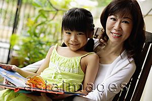 Asia Images Group - Grandmother and granddaughter, with book, looking at camera