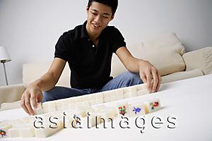 Asia Images Group - Man arranging mahjong tiles on the table