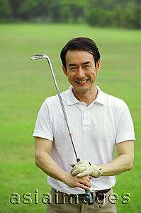 Asia Images Group - Man holding golf club, looking at camera