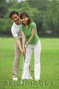 Asia Images Group - Couple playing golf, looking at camera