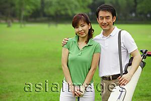 Asia Images Group - Couple standing side by side on golf course, looking at camera