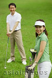Asia Images Group - Couple on golf course, smiling at camera