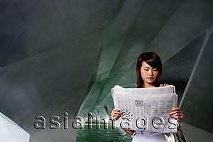 Asia Images Group - Woman in tunnel, reading newspaper