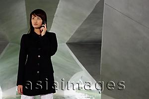 Asia Images Group - Woman in black jacket, using mobile phone, looking away