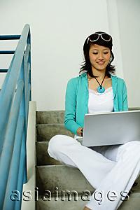 Asia Images Group - Woman sitting on stairs, using laptop