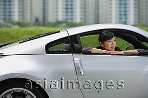Asia Images Group - Woman in front seat of silver sports car, looking out the window, smiling