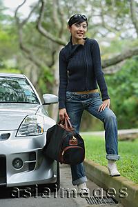 Asia Images Group - Woman holding bag, standing next to car, smiling at camera