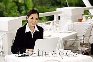 Asia Images Group - Businesswoman sitting in restaurant with laptop, looking at camera