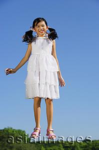Asia Images Group - Girl wearing white dress, jumping in mid air, smiling at camera