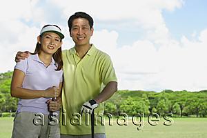 Asia Images Group - Couple standing side by side, holding golf clubs