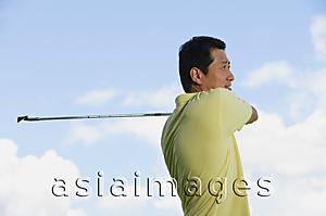 Asia Images Group - Man swinging golf club, looking away