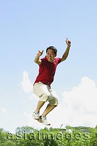Asia Images Group - Man jumping in mid air, pointing at camera