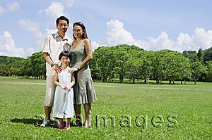 Asia Images Group - Family of three standing in field, looking at camera