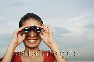 Asia Images Group - Woman looking through binoculars, head shot