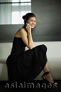 Asia Images Group - Young woman in black dress, using mobile phone