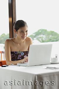 Asia Images Group - Woman sitting in restaurant, using laptop
