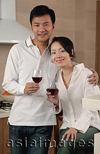 Asia Images Group - Couple in kitchen, holding wine glasses, looking at camera, portrait
