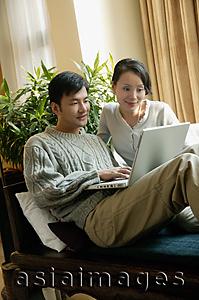Asia Images Group - Couple in living room, looking at laptop