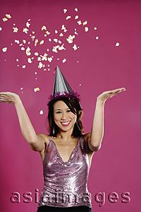 Asia Images Group - Woman wearing party hat, throwing popcorn in air