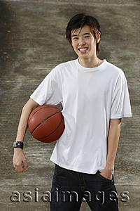 Asia Images Group - Young man with basketball, hand in pocket