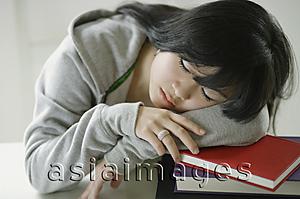 Asia Images Group - Young woman sleeping on stack of books