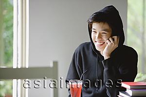 Asia Images Group - Young man with hooded jacket, drink in front of him, smiling