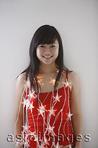 Asia Images Group - Young woman wearing fairy lights, smiling