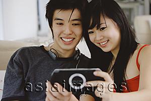 Asia Images Group - Teenage couple smiling at camera phone
