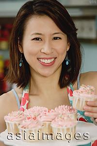 Asia Images Group - Woman holding plate of cupcakes