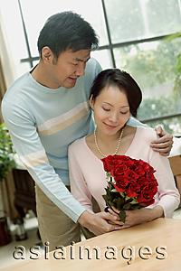 Asia Images Group - Couple at home, man giving woman bouquet of roses