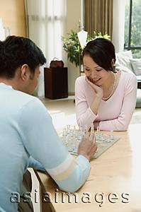 Asia Images Group - Couple sitting at table at home playing chess