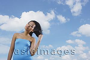 Asia Images Group - Woman in blue tube top, standing against blue sky