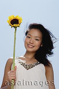 Asia Images Group - Woman holding sunflower stalk, smiling at camera