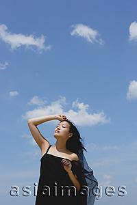 Asia Images Group - Woman in black dress, hand on head, eyes closed, head tilted back