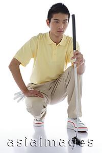 Asia Images Group - Young man crouching, holding golf club