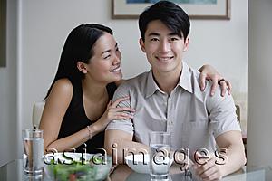 Asia Images Group - Couple at home, sitting by dining table, man looking at camera
