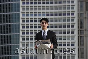 Asia Images Group - Businessman with newspaper, building in the background