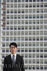 Asia Images Group - Businessman looking at camera, building behind him