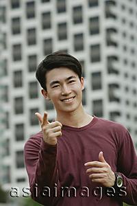 Asia Images Group - Man smiling at camera, making hand sign
