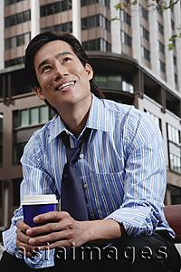 Asia Images Group - Businessman sitting in the city, holding disposable coffee cup