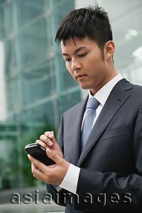 Asia Images Group - Businessman using PDA, city location