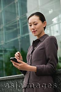 Asia Images Group - Businesswoman using PDA, city location
