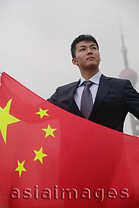 Asia Images Group - Businessman holding China flag, Oriental Pearl TV Tower in the background