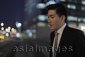 Asia Images Group - Profile of young man in front of buildings at night