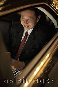 Asia Images Group - Mature man sitting in car working on laptop