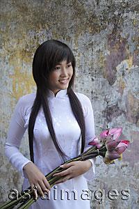 Asia Images Group - Young woman wearing traditional Vietnamese dress holding lotus flowers