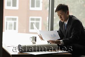 Asia Images Group - Young man working near a window in an office