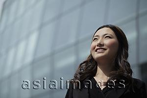 Asia Images Group - Young woman looking up smiling, building in background